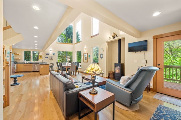 Unwind in this sun-filled retreat where soaring ceilings and plush seating surround you. The wood stove, lofted windows, and open layout create a serene, airy atmosphere perfect for your stay.