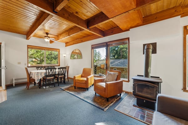 Relax in your cozy living area with vaulted wood ceilings, a warming fireplace, and inviting leather seating that opens to a sun-filled dining space—perfect for unwinding after a day of adventure.