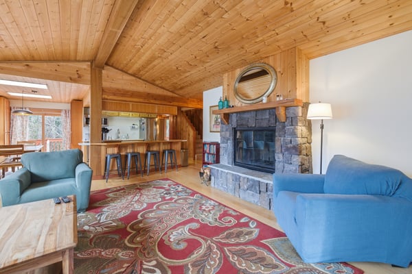 Sink into comfortable seating by your stone fireplace while warm wood beams overhead create a cozy mountain retreat atmosphere.