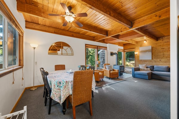Gather around the dining table under warm wooden beams while sunlight filters through large windows. The open layout flows into a comfortable living space, perfect for unwinding after your day's adventures.