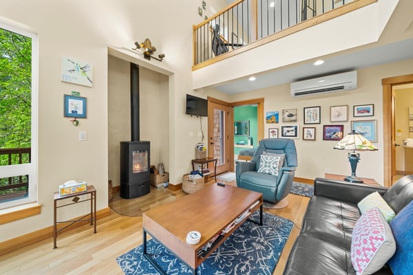 Settle into your inviting living room where high ceilings and warm wood floors create a bright, airy retreat. The cozy fireplace and comfortable seating make it your perfect spot to unwind.